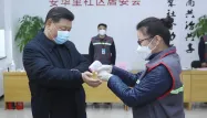 Xi Jinping en banlieue de Pékin, portant un masque et se faisant prendre sa température.