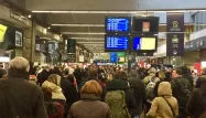 Les yeux rivés sur les écrans, à la gare Montparnasse, les voyageurs constatent les retards annoncés.