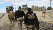 Des membres des forces irakiennes marchent vers des véhicules militaires lors des combats contre Daech à Ramadi.