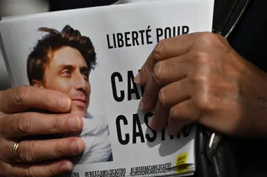 Une femme tenant dans sa main plusieurs tracts pour demander la libération de Camilo Castro.