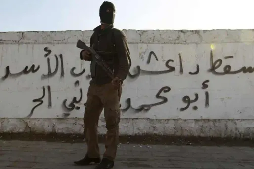 Un combattant devant un graffiti au nom de l'Etat islamique d'Irak et du Levant.