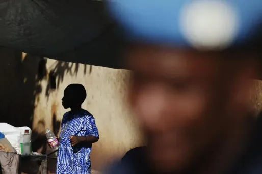 Un garçon dans l'ombre derrière un soldat au Mali