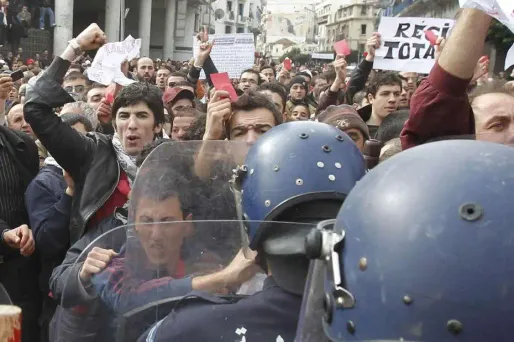 Une manifestante algérienne tend une fleur aux policiers qui lui font face, ici à Alger.
