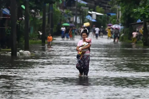 Une femme porte un enfant en traversant les inondations dans le village de Kalaw, dans l'Etat Mon, en Birmanie.