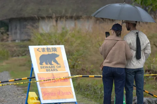 Des touristes se tenant devant un panneau "attention aux ours" à Shirakawa-go, dans l'ouest de l'île de Honshu.
